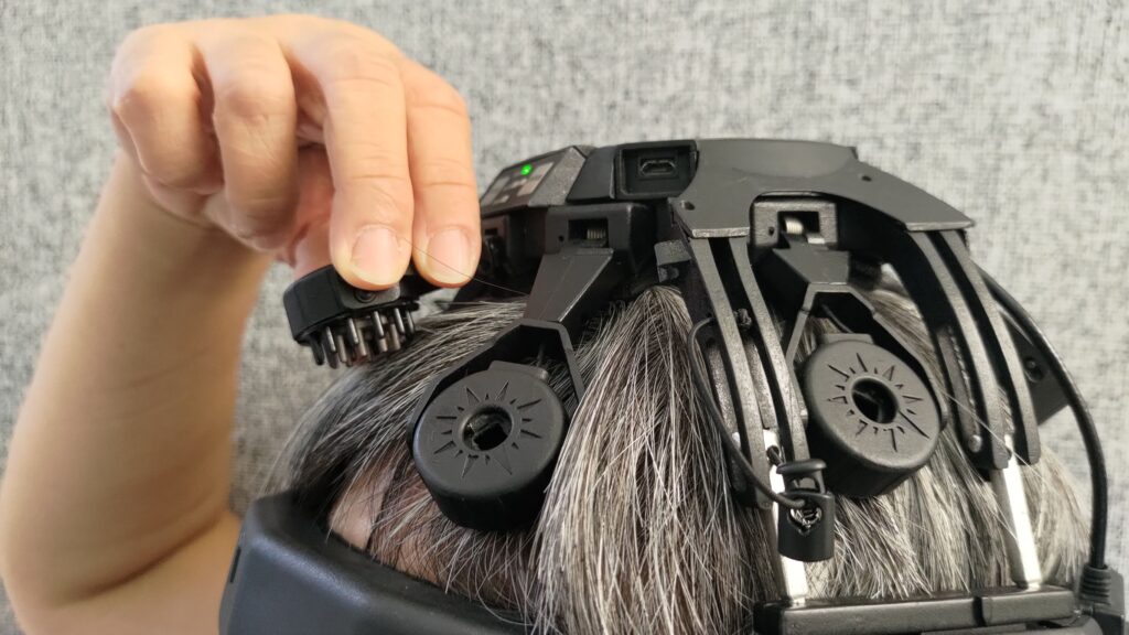 DSI-24 乾式腦波儀電極特寫，梳狀探針穿過頭髮直接接觸頭皮，示範乾式腦波檢測不需塗抹導電膠的配戴方式