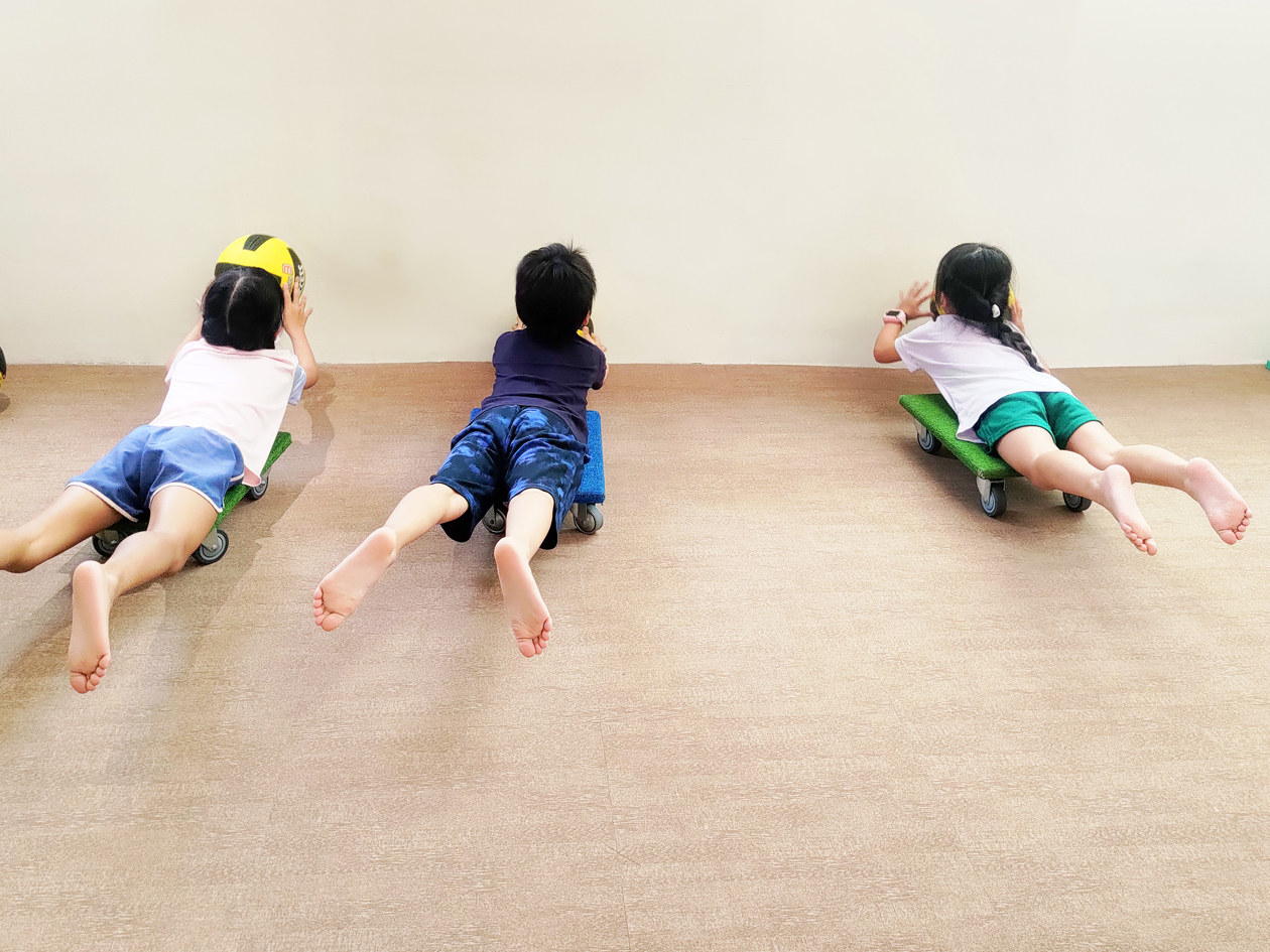孩子趴在滑板車上進行平衡與動作協調的感覺動作訓練